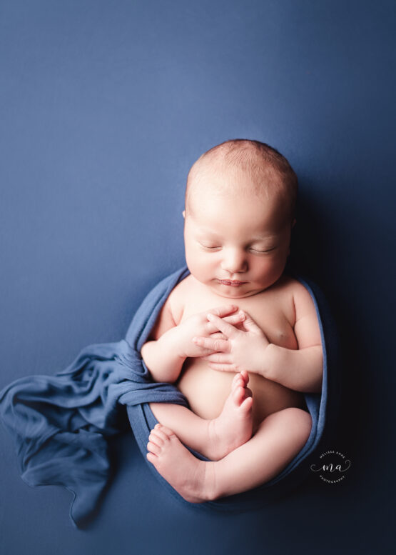 Michigan newborn photographer Melissa Anne Photographer baby boy egg wrap pose on dark blue