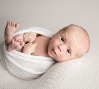 Troy Michigan newborn photographer Melissa Anne Photography wrapped baby Huck Finn pose on cream backdrop