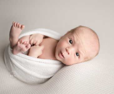 Troy Michigan newborn photographer Melissa Anne Photography wrapped baby Huck Finn pose on cream backdrop