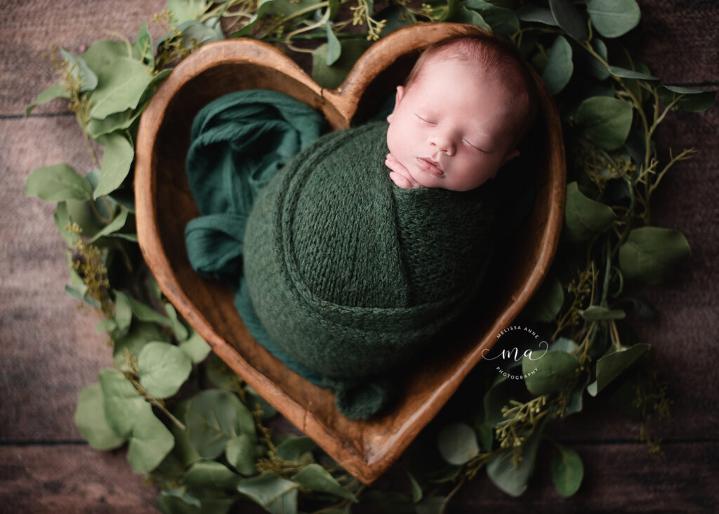 Michigan newborn photographer Melissa Anne Photography baby boy in wood heart bowl with greenery