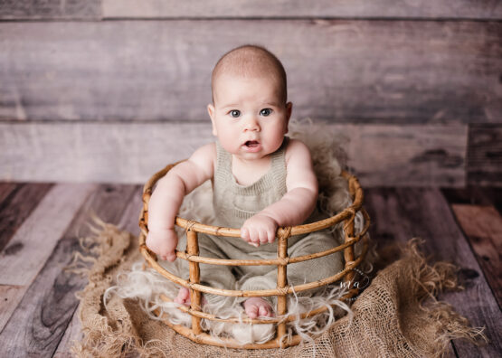 Metro Detroit Michigan baby photographer Melissa Anne Photography six month old boy on wood backdrop in bamboo basket with overalls