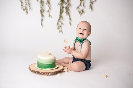 metro Detroit baby photographer Melissa Anne Photography cake smash one year old photo session with greenery on white backdrop