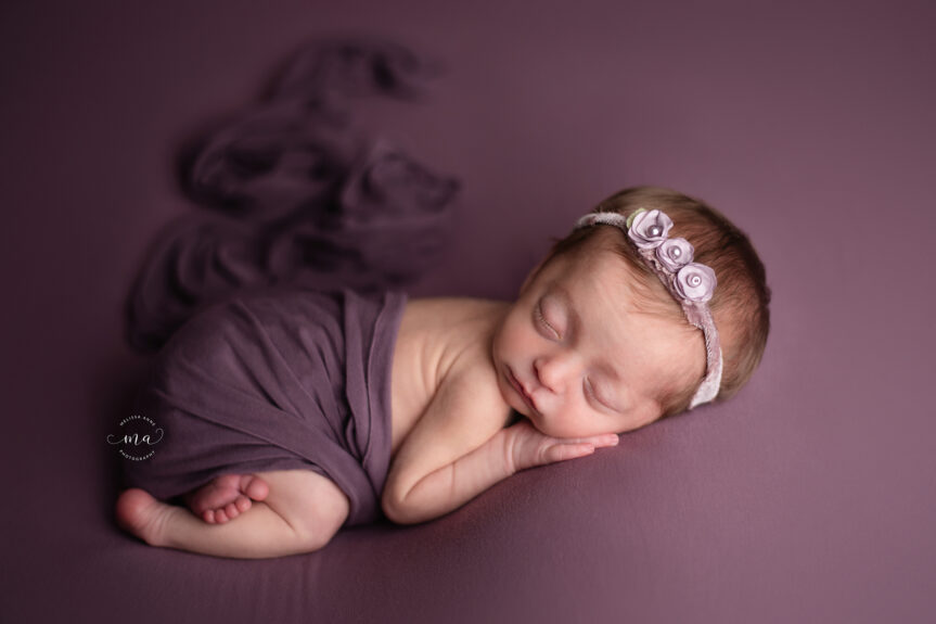 Troy Michigan newborn photographer Melissa Anne Photography baby girl on purple background tushie up pose with headband