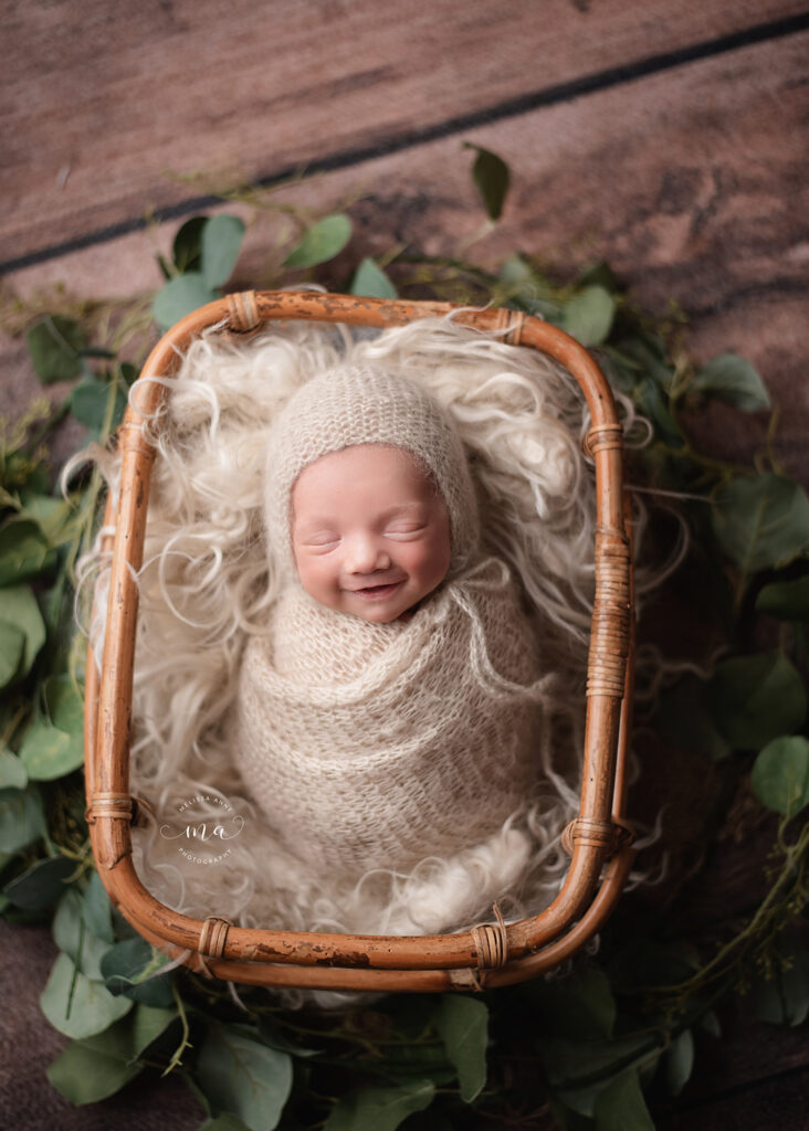 Troy Michigan newborn photographer Melissa Anne Photography newborn baby boy in basket with bonnet smiling