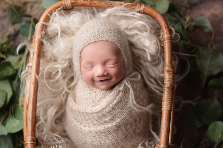 Troy Michigan newborn photographer Melissa Anne Photography newborn baby boy in basket with bonnet smiling