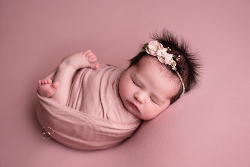 West Bloomfield Michigan newborn photographer Melissa Anne Photography newborn baby girl in wrap with floral headband on pink background