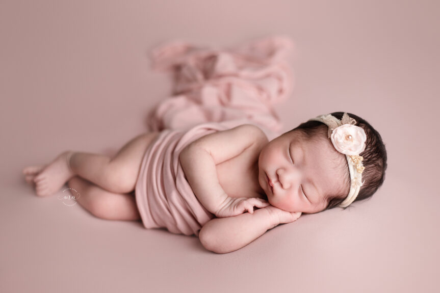 Metro Detroit Michigan newborn photographer Melissa Anne Photography side lay pose with baby girl with pink backdrop and flowing drape